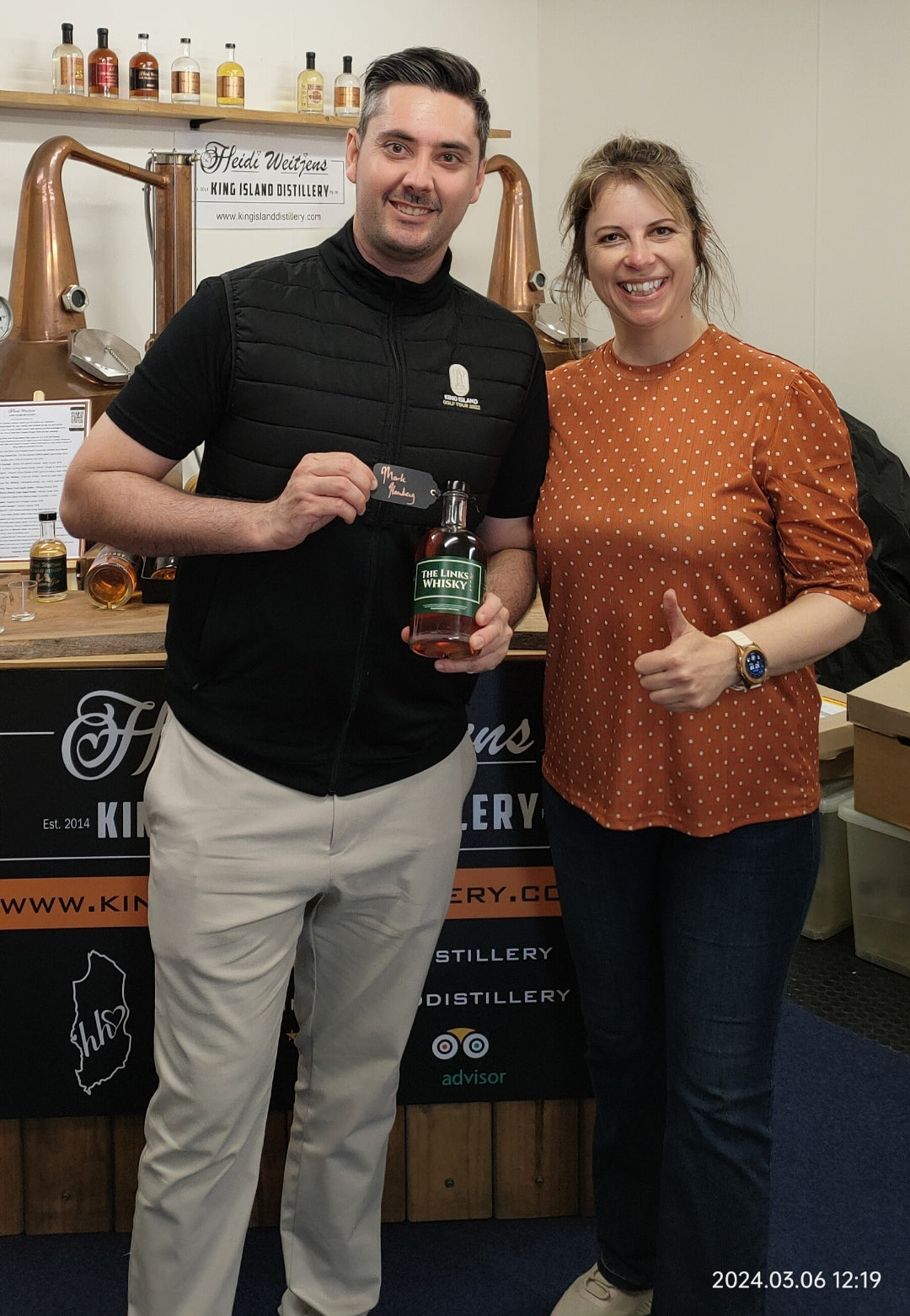 Mark Hawley and Heidi Weitjens at King Island Distillery: Mark Hawley holds a bottle of Golf Links Whisky next to Heidi Weitjens, showcasing their collaboration.