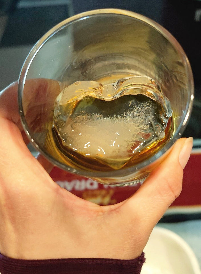 Happy Heidi holding a glass at King Island Distillery, crafted with King Island Rainwater with barrel aged King Island Native Gin over King Island Rainwater love heart ice cube